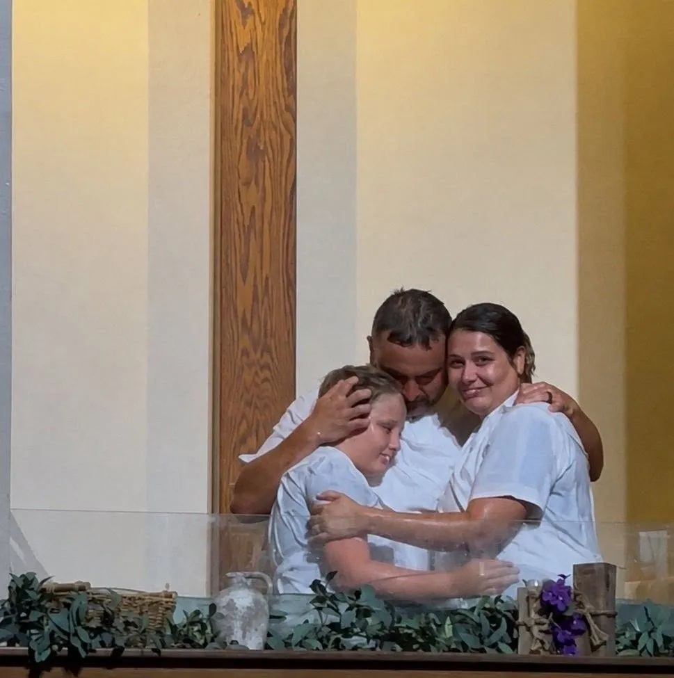 Joey and Laurin embracing their son Lucas after the family was baptized together